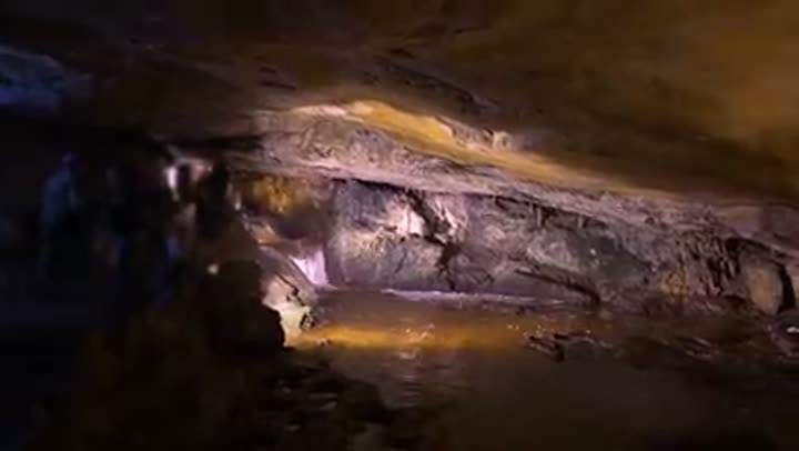 An illuminated underground river flowing through a mysterious cave system in Arkansas.