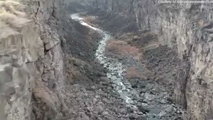 A dramatic river carves through a deep, rocky canyon, highlighting Idaho's rugged terrain.